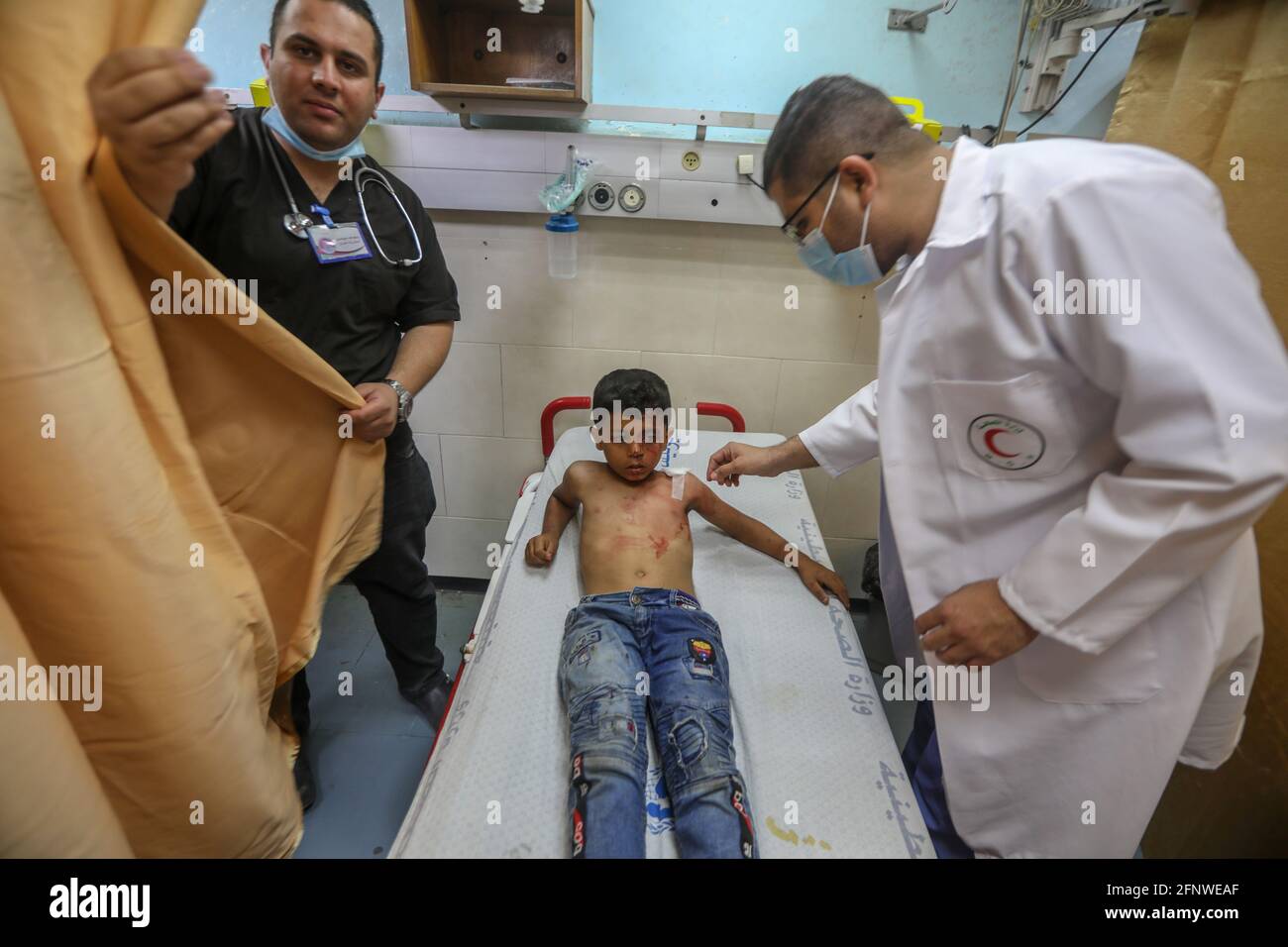 Gaza. 19 mai 2021. Un enfant palestinien a été blessé en jouant près de la porte de sa maison après que des avions de guerre israéliens l'ont pris pour cible avec un certain nombre d'enfants dans le quartier d'Al-Zaytoun, à l'est de la ville de Gaza. Banque D'Images