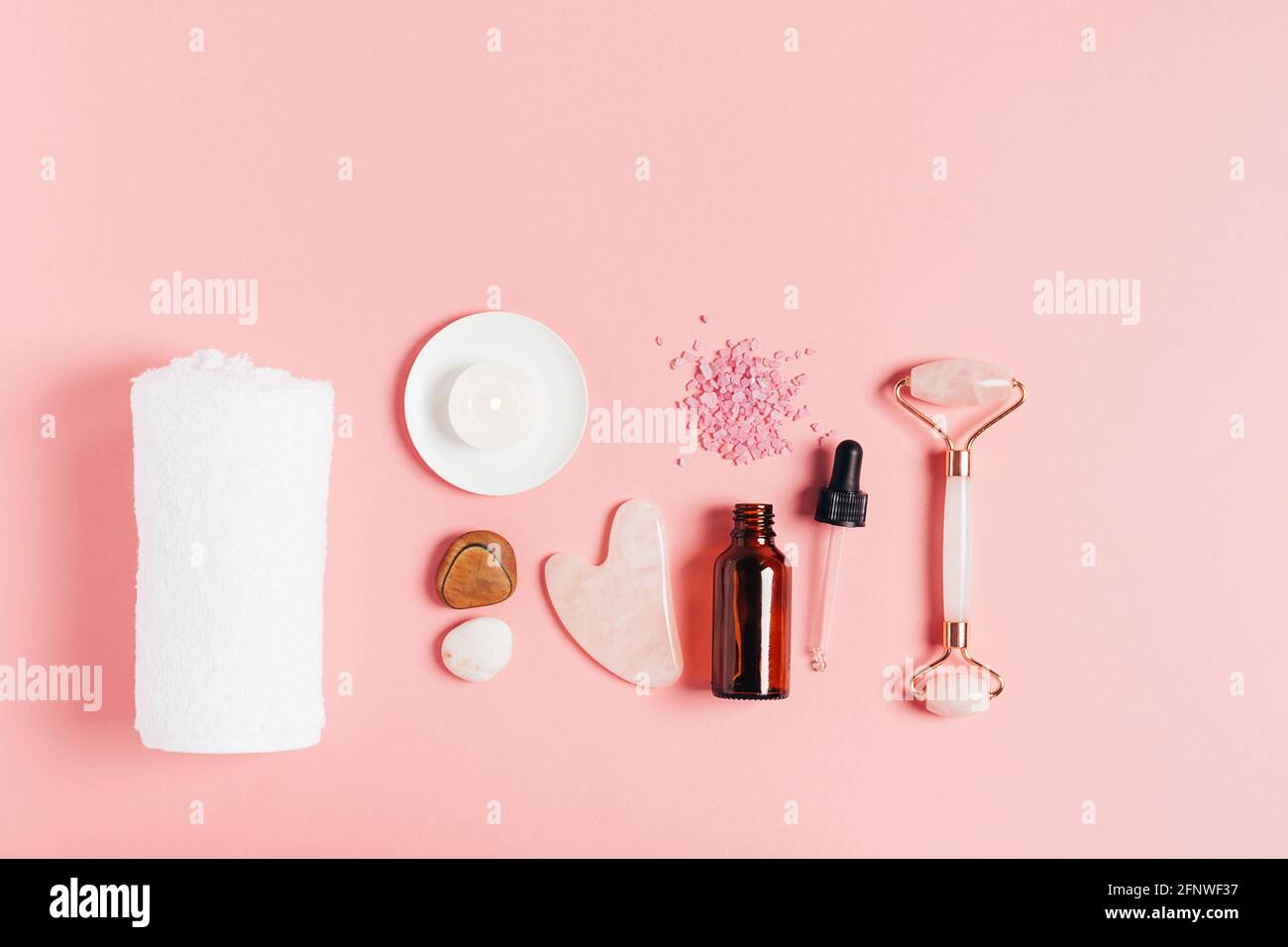 Composition spa sur fond rose pastel. Cosmétiques naturels bio bouteille d'huile, crème, argile, sel, outil de massage gua sha accessoires plan Banque D'Images