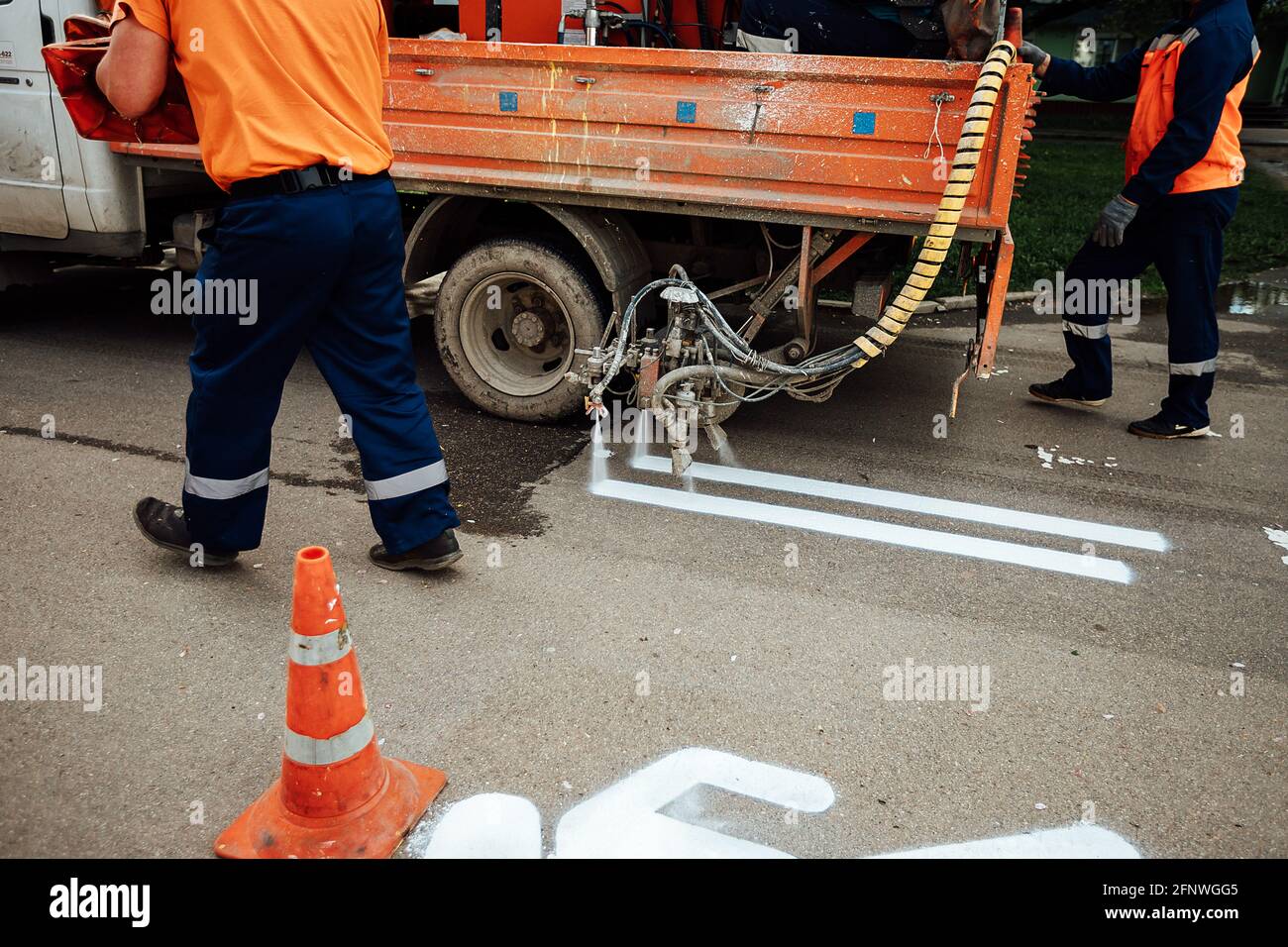 nouveau marquage de la voie piétonne sur l'asphalte. les ouvriers ont peint le symbole de l'homme avec de la peinture blanche. le cône orange avertit des travaux de voirie Banque D'Images