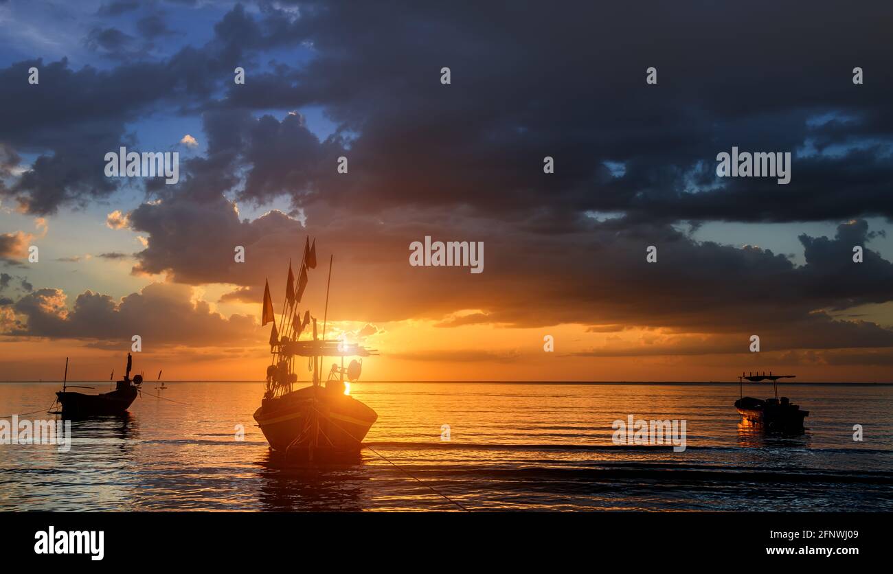 Bateaux de pêche Silhouette dans la mer avec coucher de soleil lumière chaude et ombre sombre. Banque D'Images