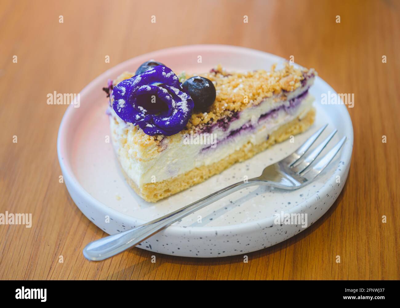 Gâteau au fromage aux baies bleues dans un plat blanc sur une table en bois. Banque D'Images