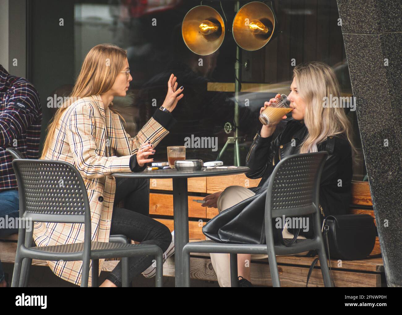 Deux belles filles sans masque, assis et buvant du café dans un bar, un café ou un restaurant en plein air après des restrictions de quarantaine Banque D'Images