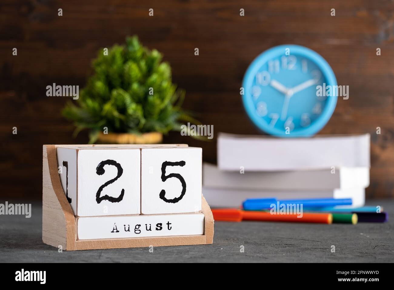 25 août. Août 25 calendrier cube en bois avec des objets flous sur fond. Banque D'Images