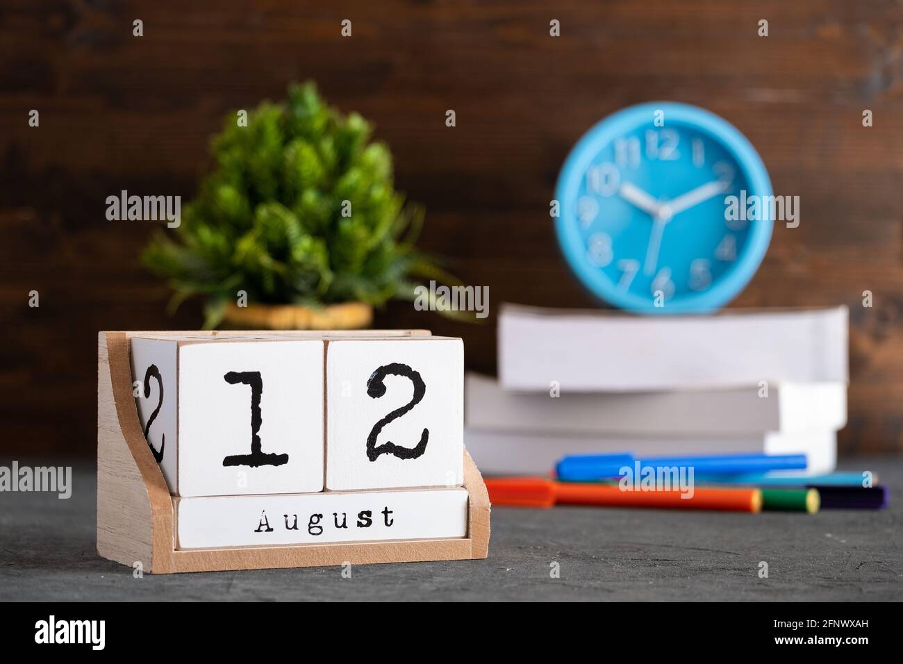 12 août. Août 12 calendrier cube en bois avec des objets flous sur fond. Banque D'Images