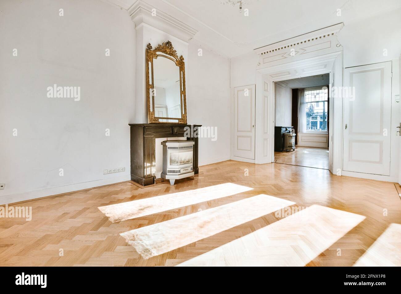 Miroir vintage placé sur une cheminée décorative en bois dans un grand couloir murs blancs avec éléments en stuc classiques et parquet Banque D'Images