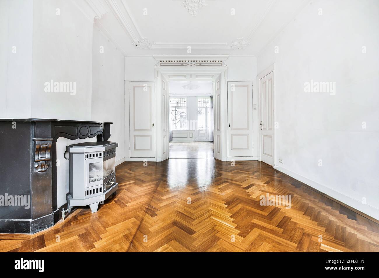 Décoration intérieure classique avec couloir spacieux et murs blancs et éléments décoratifs en stuc avec parquet meublé avec cheminée Banque D'Images