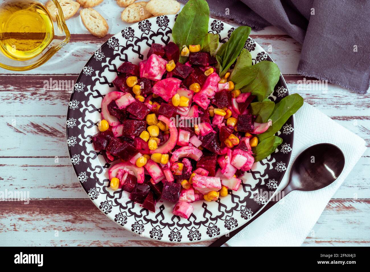 Salade de betteraves, ananas, maïs et chicorée à l'huile d'olive et au basilic sur une assiette sur une table rustique dans le style de la vie plate. Concept de légumes sains. Banque D'Images