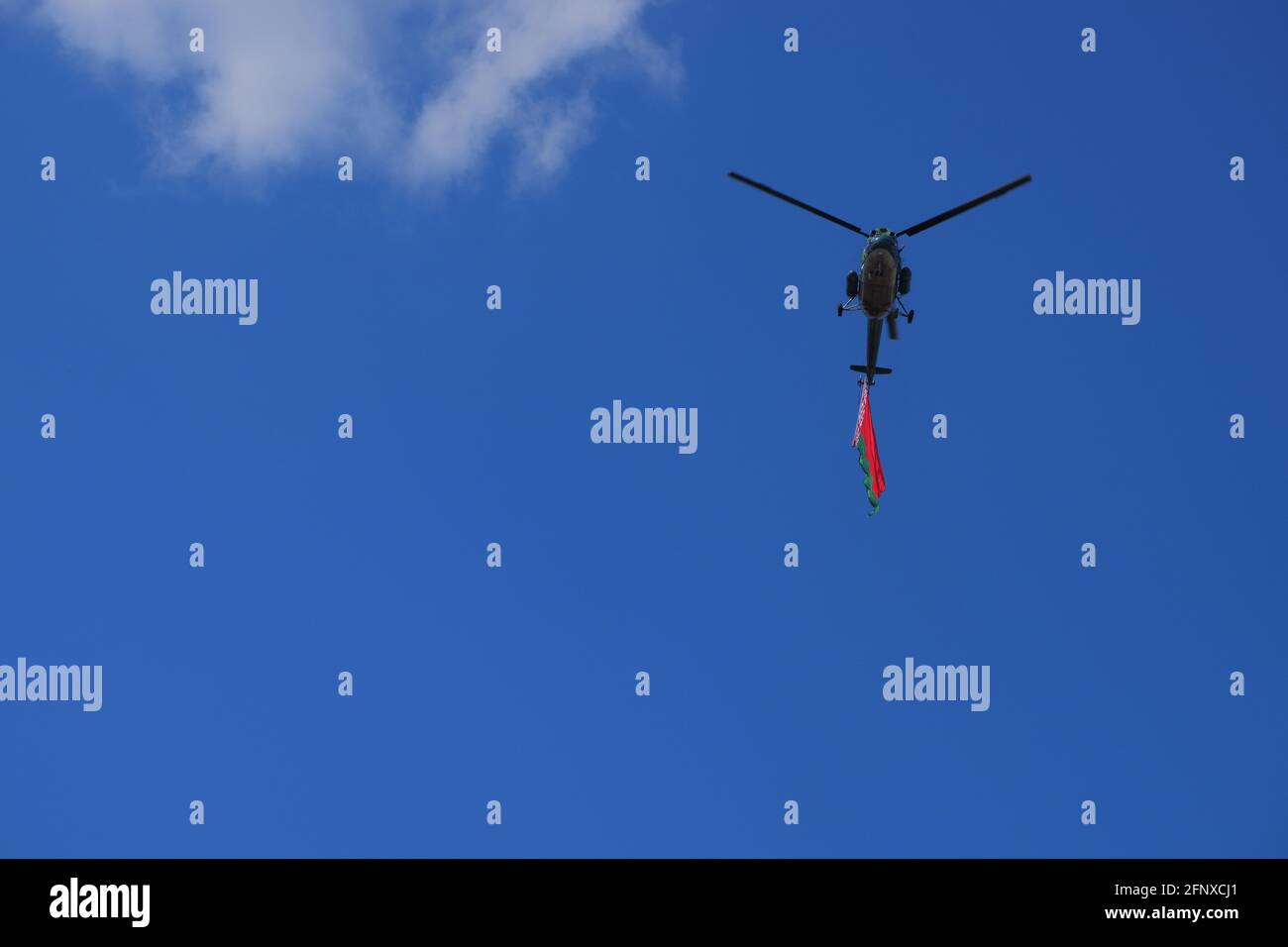 Un hélicoptère volant contre un ciel bleu avec le drapeau biélorusse. Banque D'Images