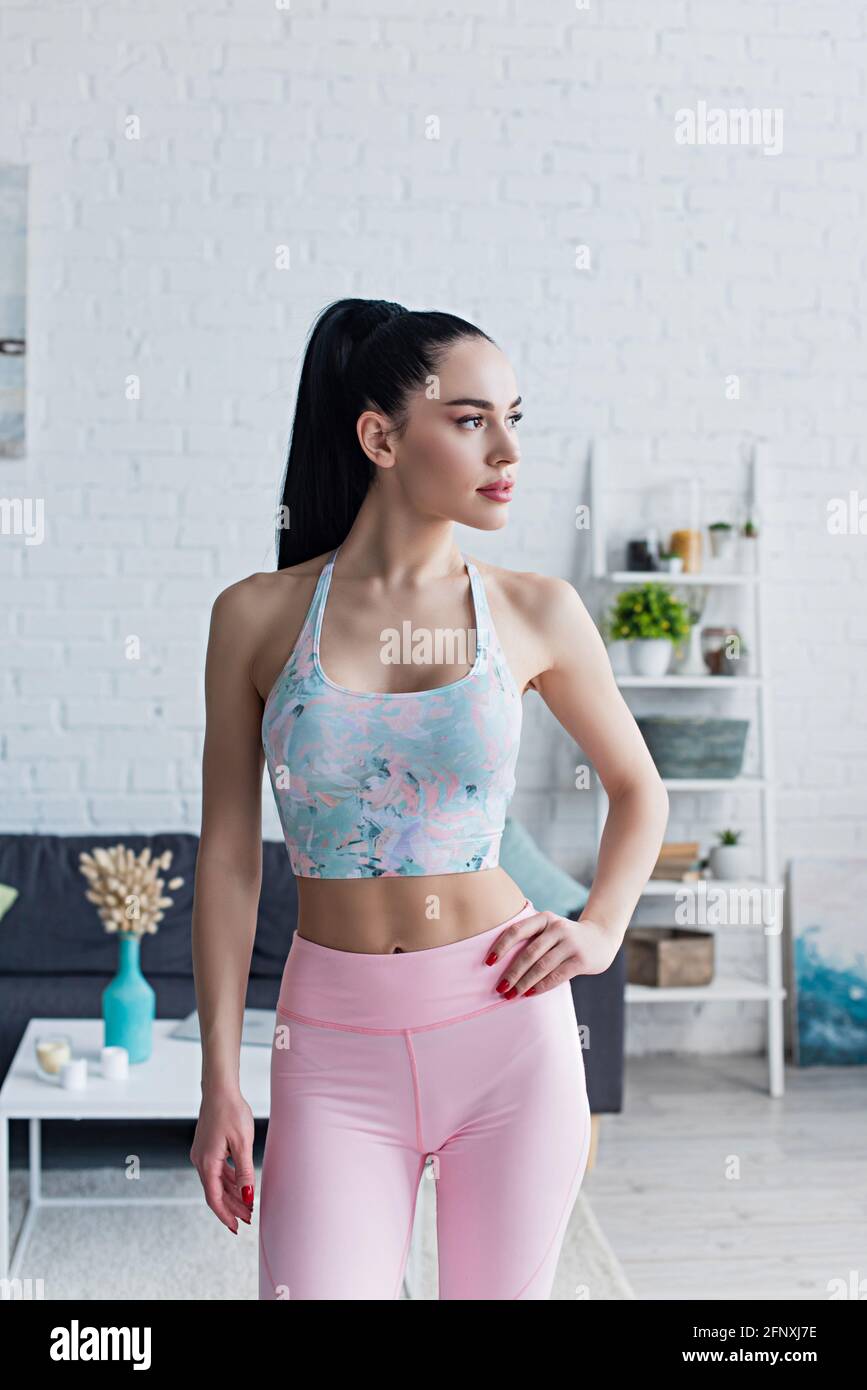 femme sportive en soutien-gorge de sport debout avec la main sur la hanche et regarder loin de chez soi Banque D'Images
