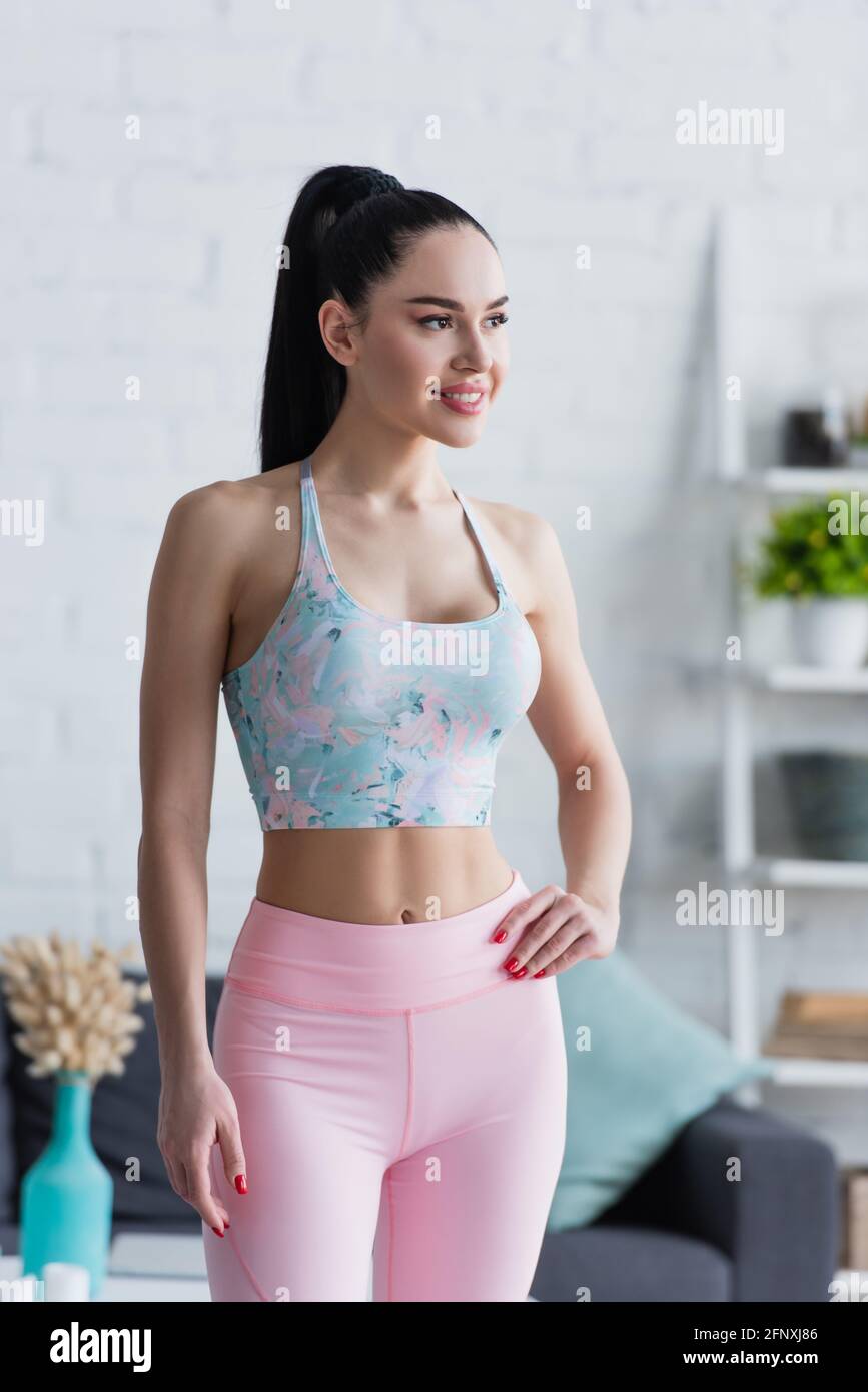 jeune femme en vêtements de sport souriant tout en se tenant à la main hanche Banque D'Images