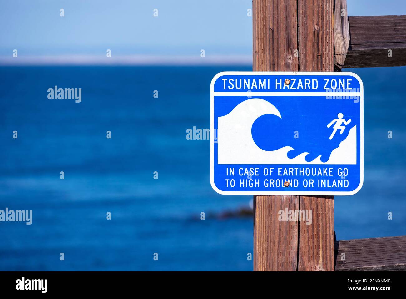 Le panneau d'avertissement de la zone de danger du tsunami sur la côte de l'océan Pacifique avertit le public d'un danger possible après un tremblement de terre. Bleu océan en arrière-plan Banque D'Images
