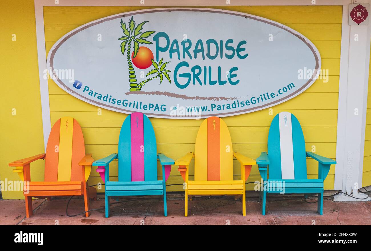 Des chaises de plage colorées sont placées sous le panneau Paradise Grill Passez UNE grille Florida Banque D'Images