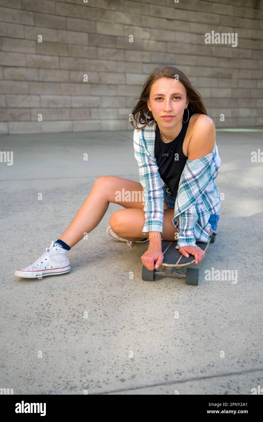 Jeune femme posant avec son skateboard dans un cadre urbain Photo Stock -  Alamy