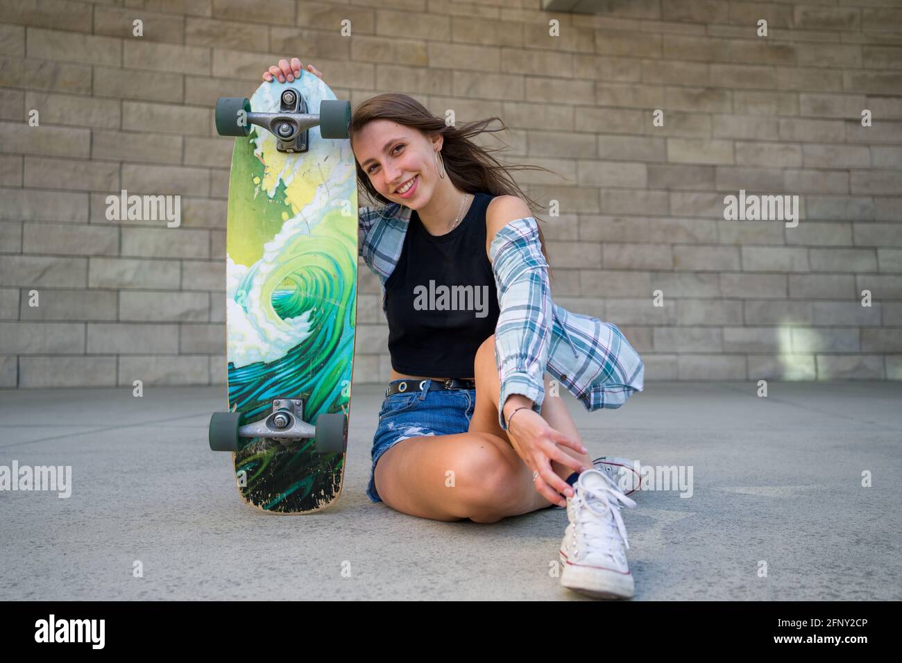 Jeune femme posant avec son skateboard dans un cadre urbain Photo Stock -  Alamy