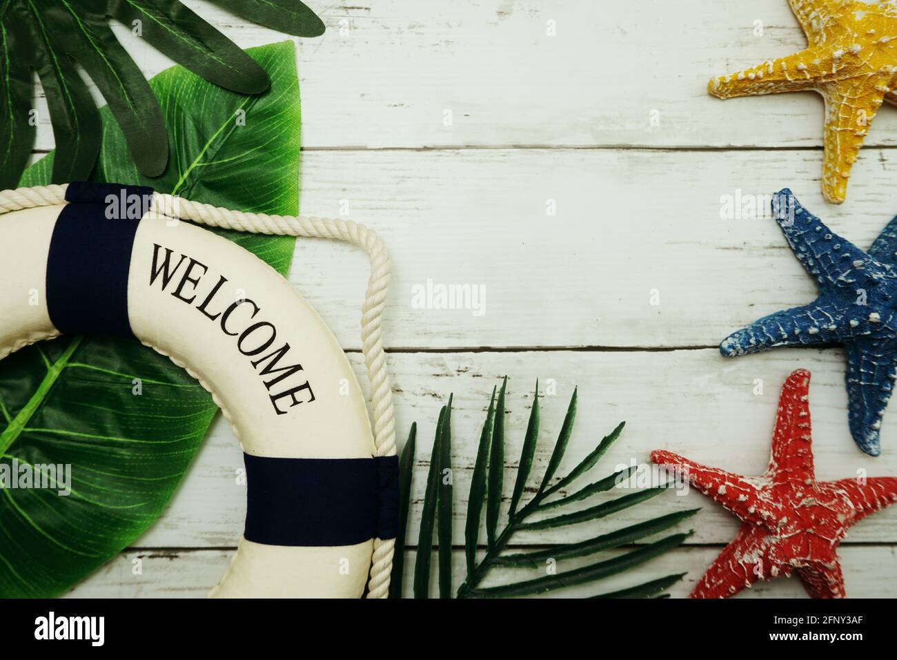 Bonjour texte d'été dans la boîte à lumière avec feuille verte, étoile de mer et décoration de bouée de sauvetage sur fond en bois Banque D'Images