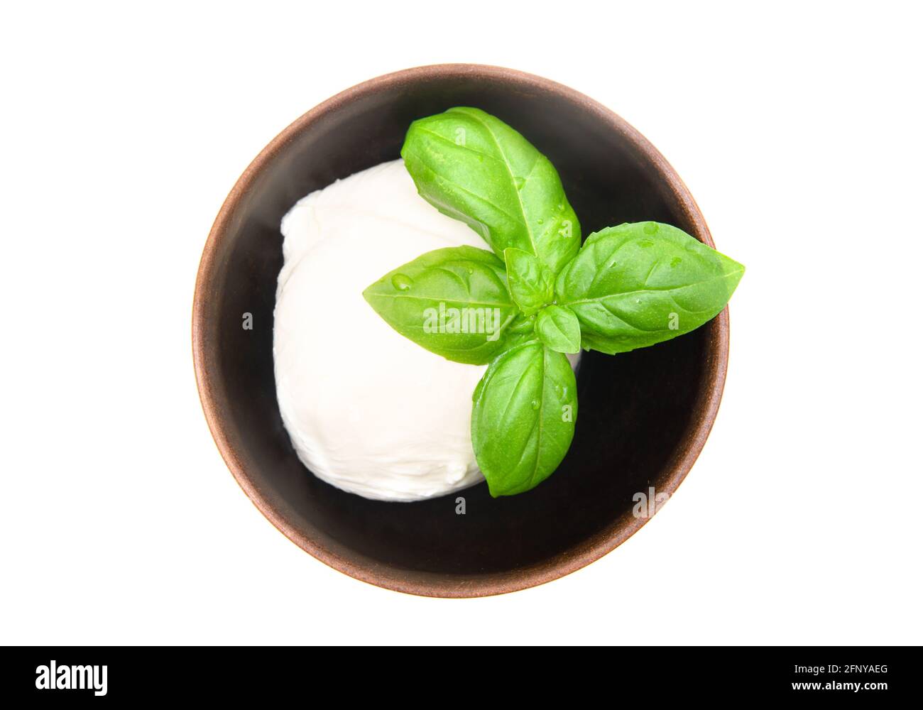 Boule de mozzarella avec feuilles de basilic frais sur le dessus dans un petit bol en bois isolé sur blanc. Vue de dessus, gros plan. Banque D'Images