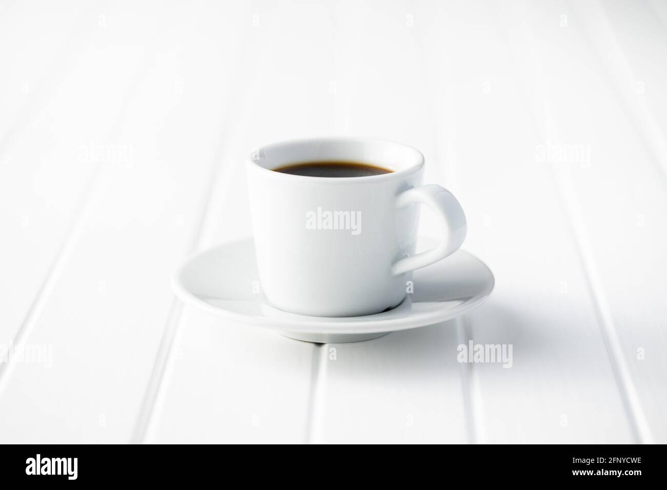 Café noir dans une tasse blanche sur une table en bois blanc. Banque D'Images