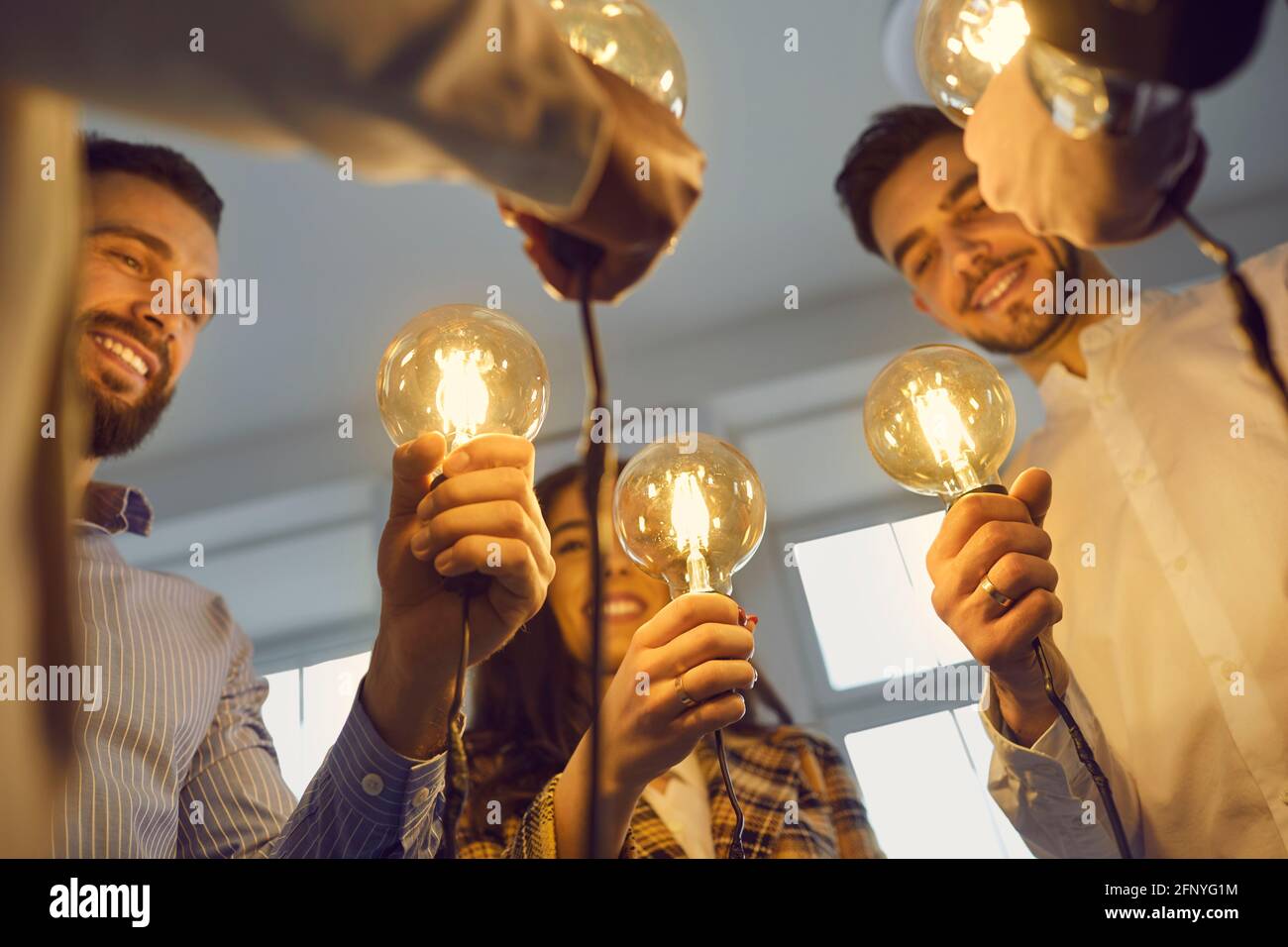 Photo conceptuelle d'une équipe d'hommes et de femmes d'affaires heureux porte-ampoules idea Banque D'Images