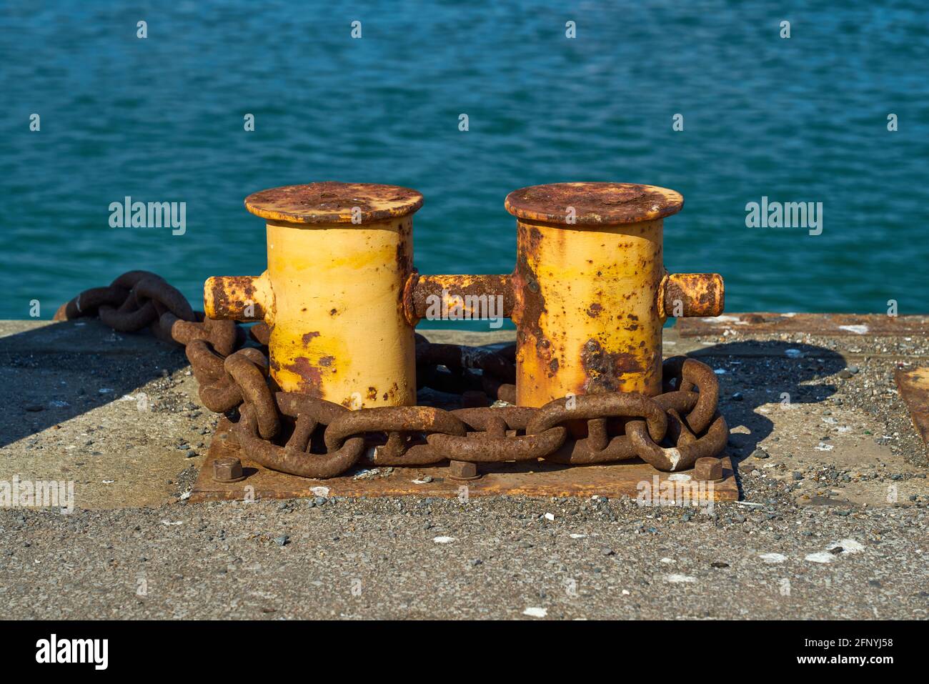 Un double bollard d'amarrage de bitt avec une chaîne lourde autour d'elle. Banque D'Images