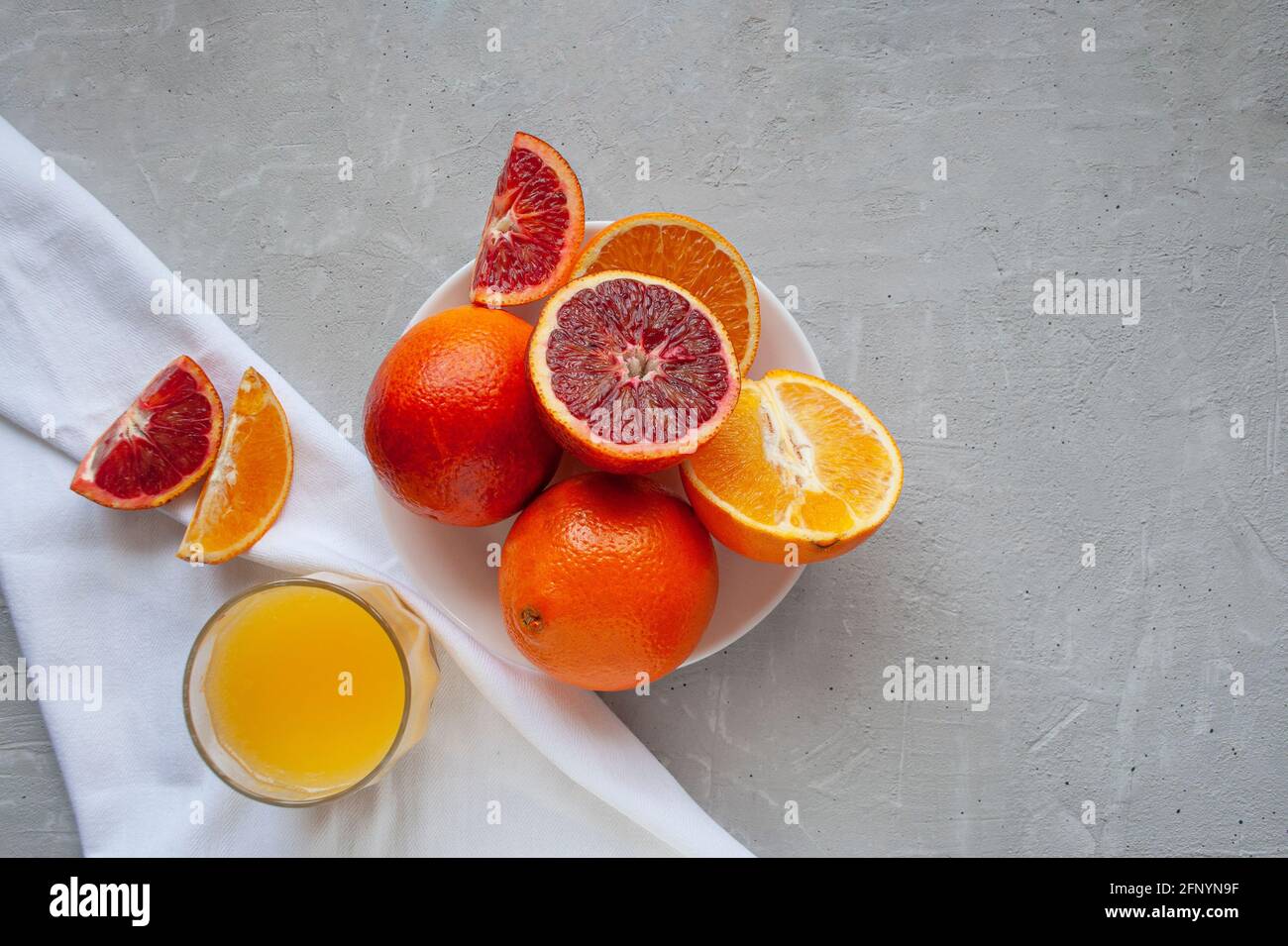 Oranges et oranges de sang sucrées et juteuses, entières et coupées sur une assiette blanche et des verres de jus d'orange frais. Jus d'orange frais avec des tranches d'oranges. Banque D'Images