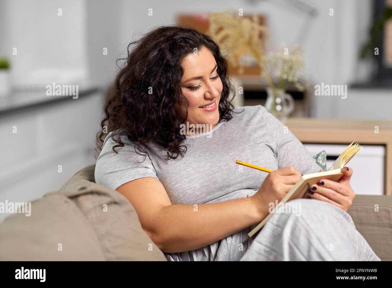 jeune femme heureuse avec journal sur le canapé à la maison Banque D'Images