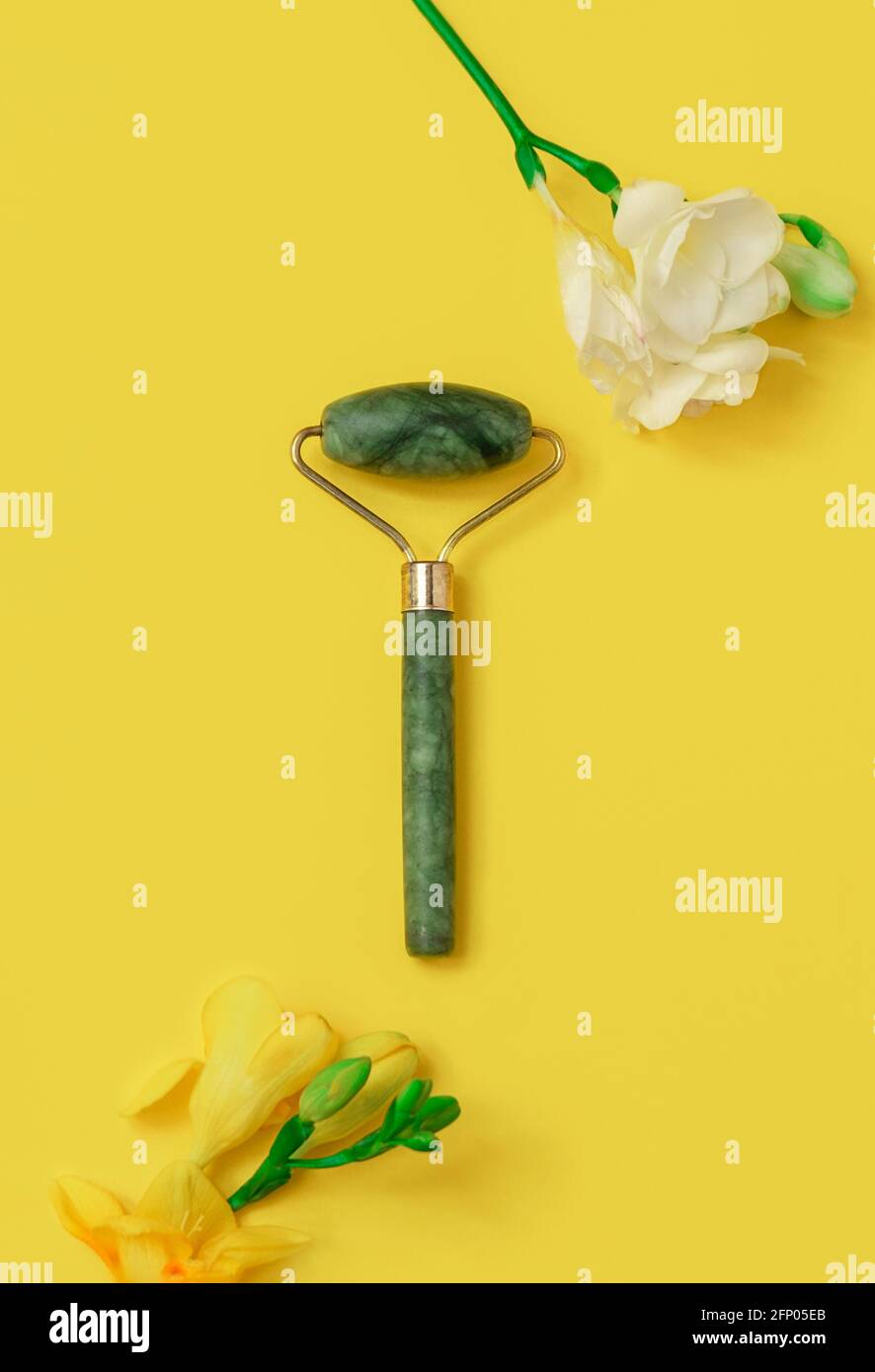 Rouleau de jade vert naturel avec fleurs sur fond jaune, vue de dessus, image verticale Banque D'Images