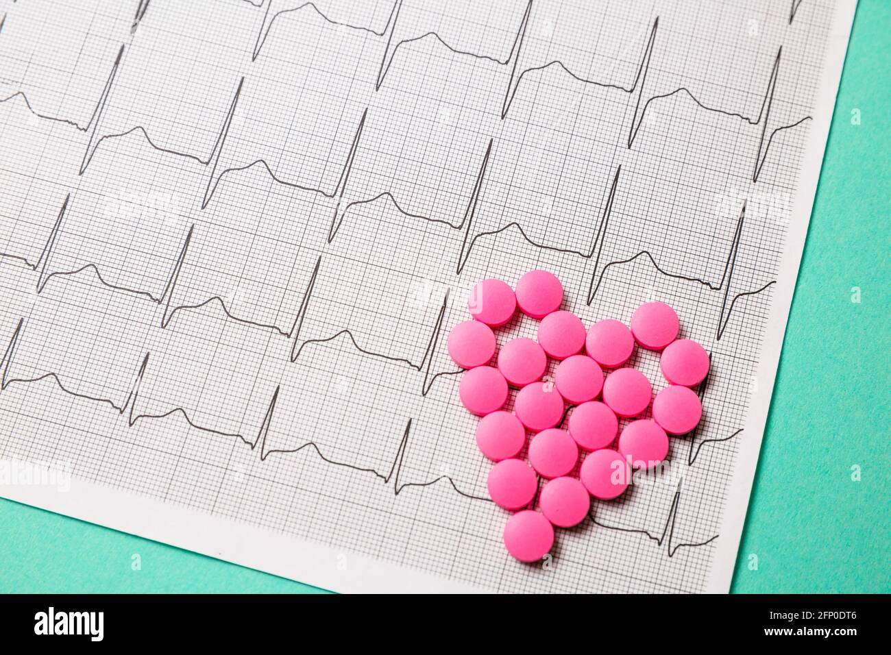 Une pile de pilules rouges en forme de coeur sur le cardiogramme. Concept médical. Banque D'Images