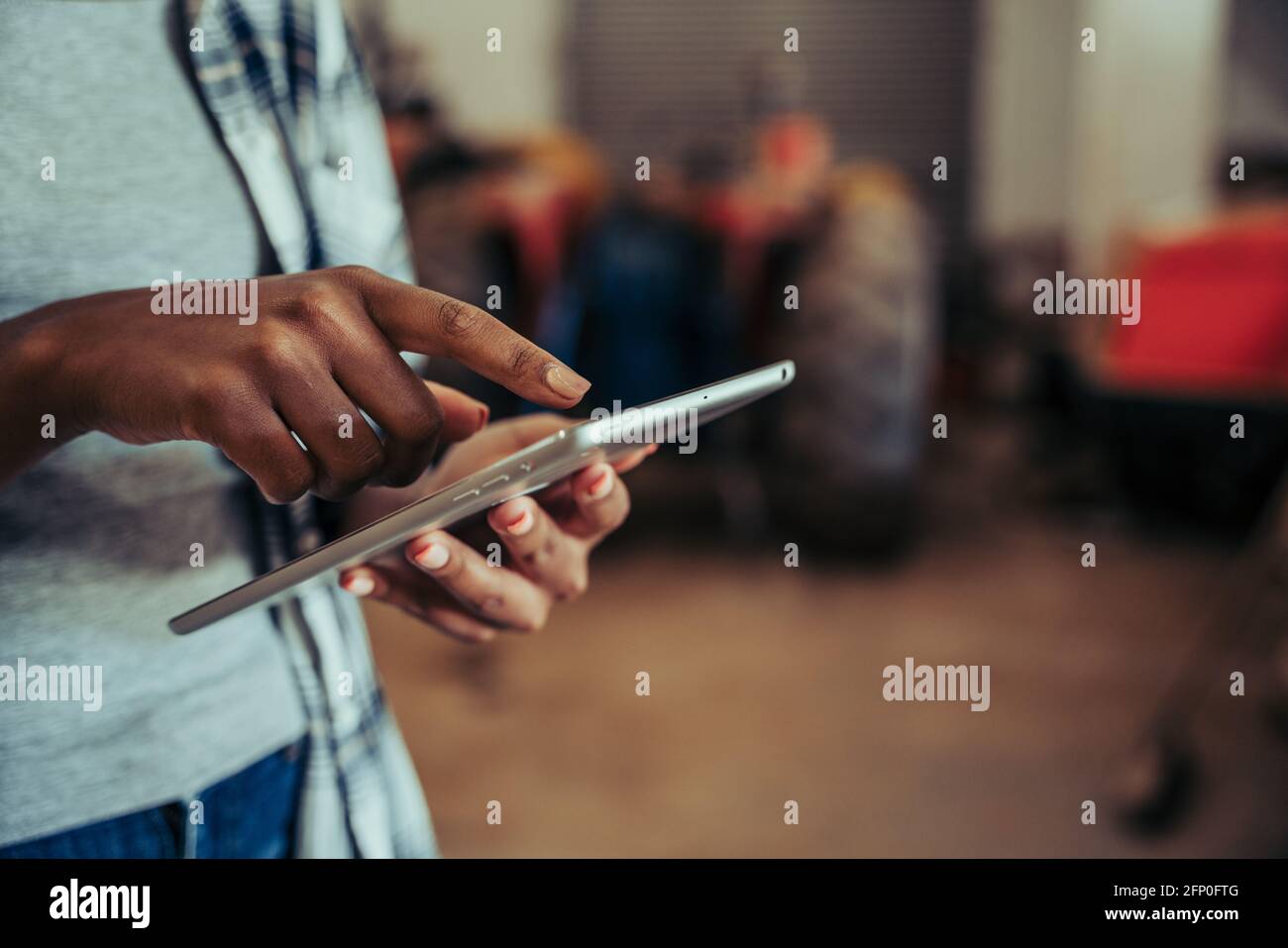 Gros plan sur la saisie féminine mixte sur une tablette numérique debout dans la salle de la ferme Banque D'Images