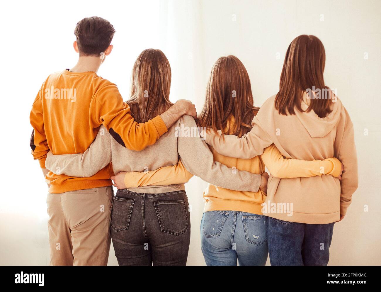 Vue arrière de l'homme anonyme et des femmes s'embrassant tout en symbolisant l'unité sur fond blanc Banque D'Images