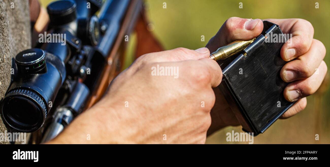 L'homme charge un fusil de chasse. Chasseur masculin prêt à chasser. Gros plan. Munitions avec un pistolet, cartouches. Chasseur. Période de chasse. L'homme est allumé Banque D'Images