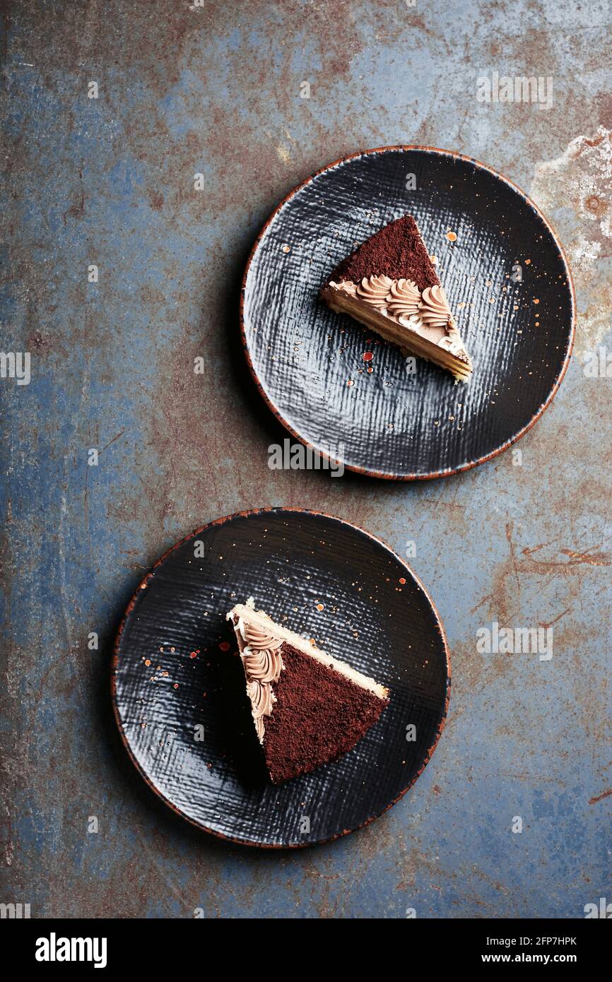 Deux morceaux de gâteau au chocolat sur des assiettes noires, vue du dessus. Banque D'Images
