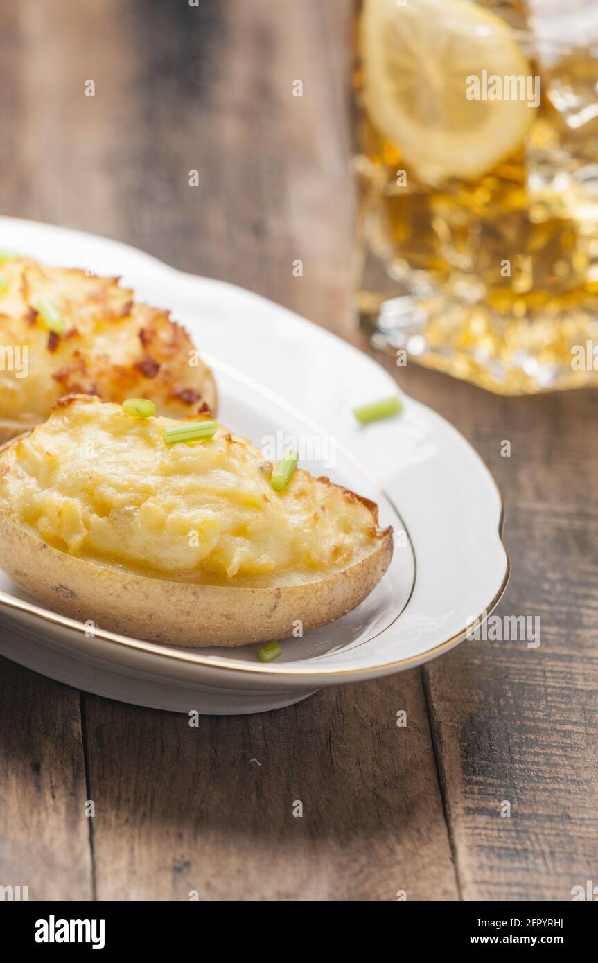 Prise verticale d'une assiette de pommes de terre cuites au four farcies fromage et œufs Banque D'Images