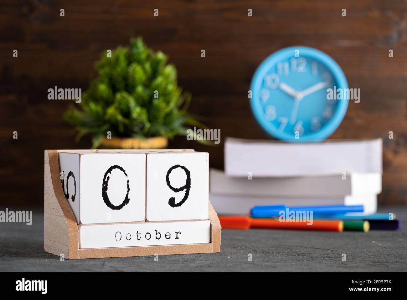 Le 09 octobre. Octobre 09 calendrier cube en bois avec objets flous sur fond. Banque D'Images