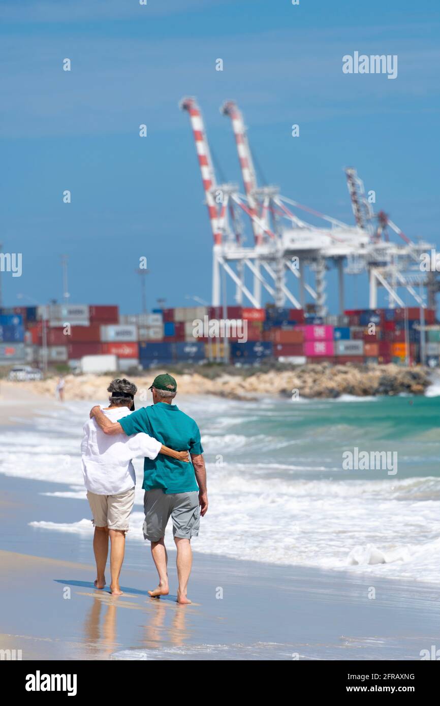 Couple d'âge mûr marchez le long de Port Beach près de Fremantle avec le port en arrière-plan. Banque D'Images
