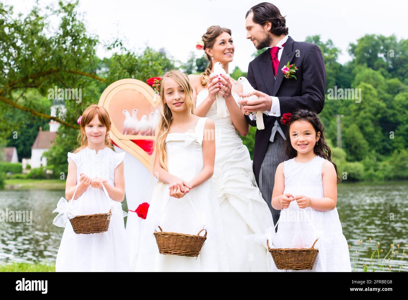 Mariage mariée et marié avec fleurs enfants ou demoiselle d'honneur et colombes blanches de la paix Banque D'Images