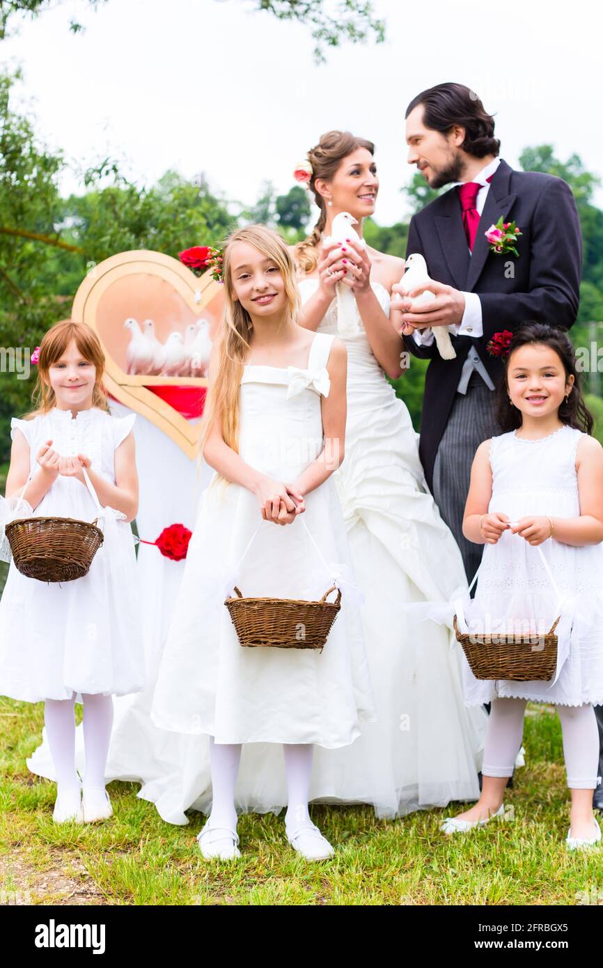 Mariage mariée et marié avec fleurs enfants ou demoiselle d'honneur et colombes blanches de la paix Banque D'Images