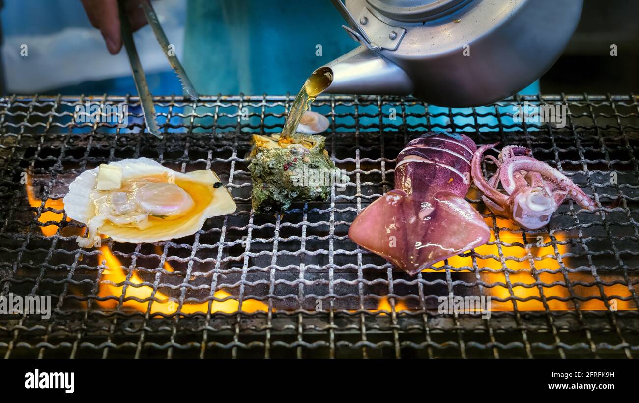 Un vendeur de rue prépare des fruits de mer sur un grill à l'île Enoshima au Japon. Banque D'Images