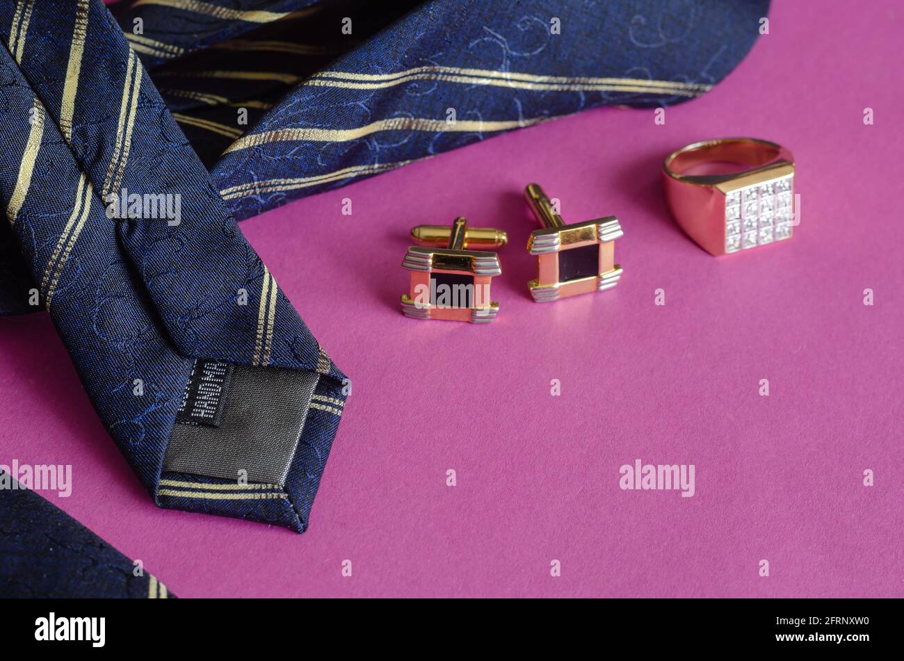 Cravate bleue avec rayures jaunes, anneau doré et boutons de manchette sur  fond rose. Accessoires pour hommes Photo Stock - Alamy