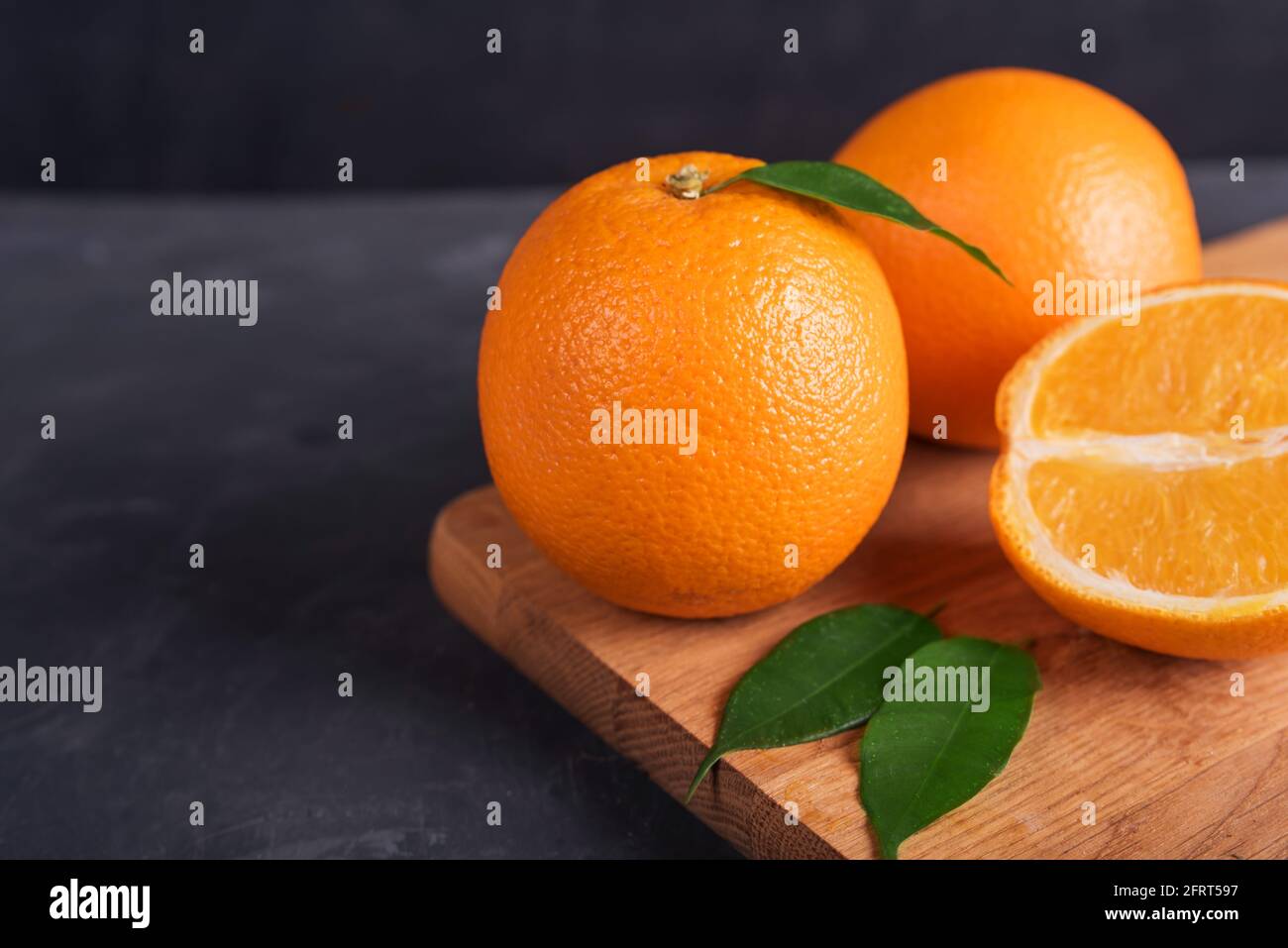 Fruits frais à l'orange avec feuilles sur une table en bois Banque D'Images