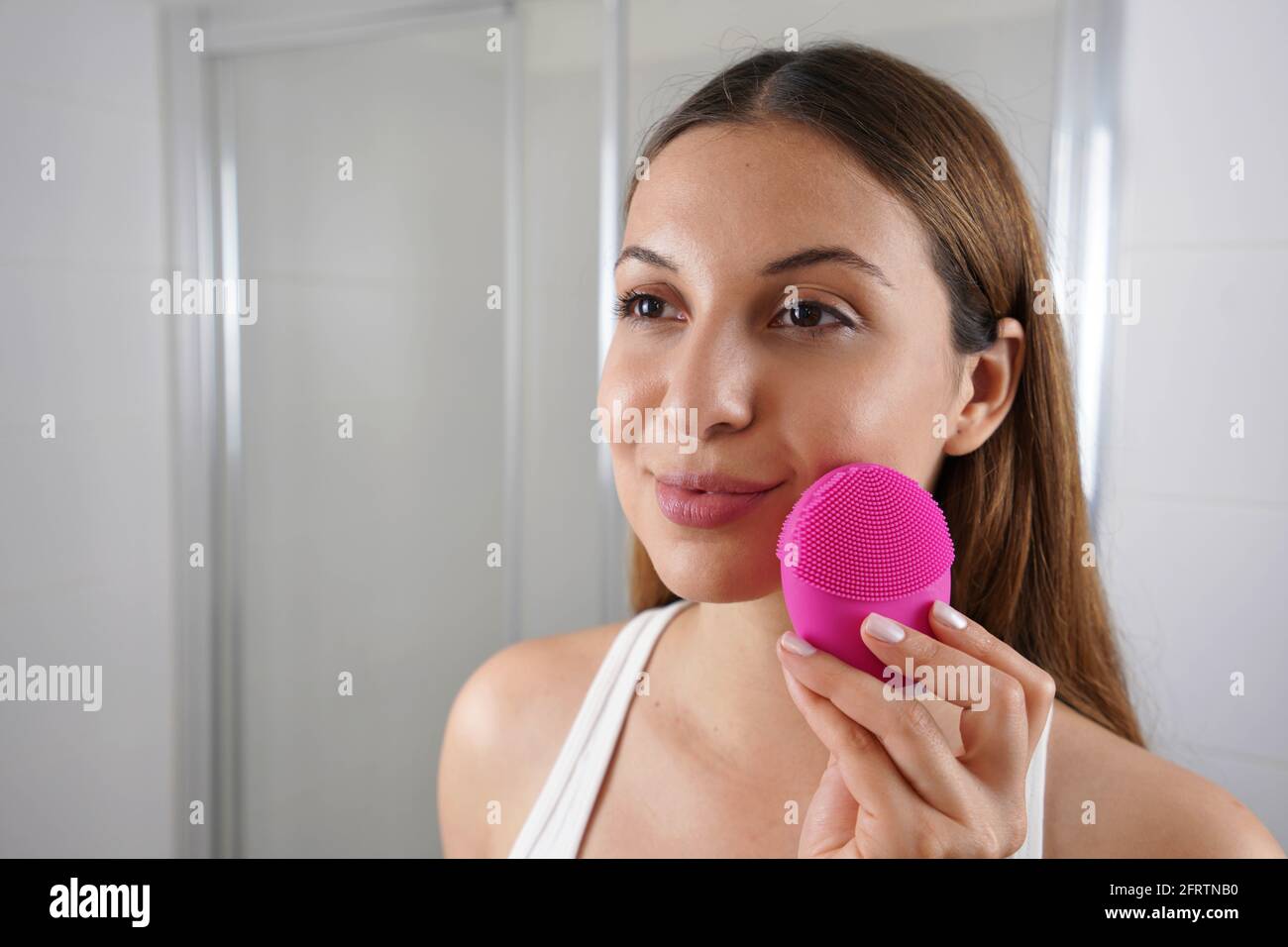 Gros plan de la jeune femme nettoyant la peau avec la brosse en silicone vibrateur ultrasonique dans la salle de bains. Concept de soin et de bien-être de la peau. Banque D'Images