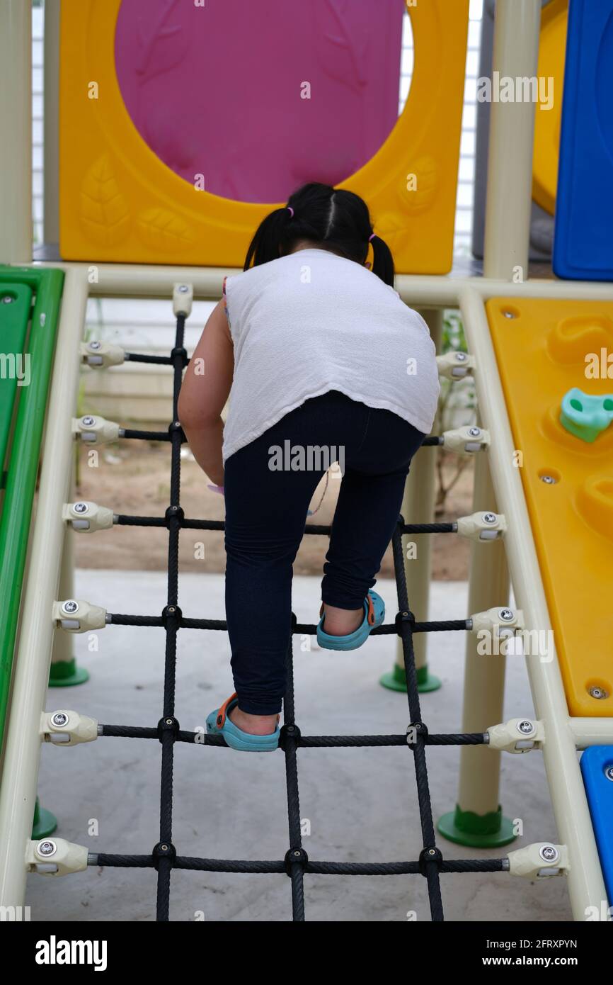 Une Vue Arriere D Une Jeune Fille Asiatique Adorable Qui Grimpe Sur Une Rampe D Acces Dans Une Grande Salle De Gym De Jungle Exterieure Coloree Se Rendant Au Sommet De La Structure Photo