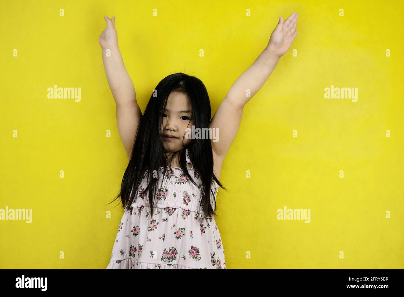 Une jeune fille asiatique mignonne soulève les deux mains, souriant, se sentant heureuse après avoir terminé avec succès son projet de mission. Jaune clair ba Banque D'Images