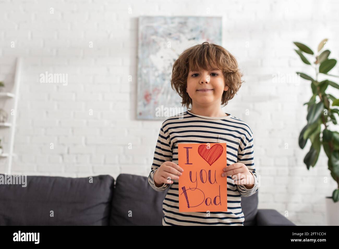 Un garçon souriant tenant une carte cadeau avec moi, je t'aime papa lettrage Banque D'Images