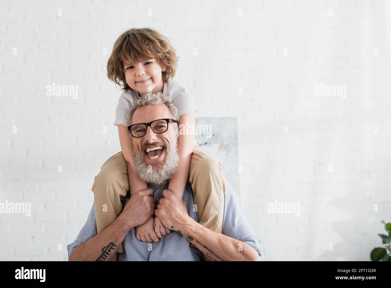 Homme positif tenant un enfant souriant à la maison Banque D'Images
