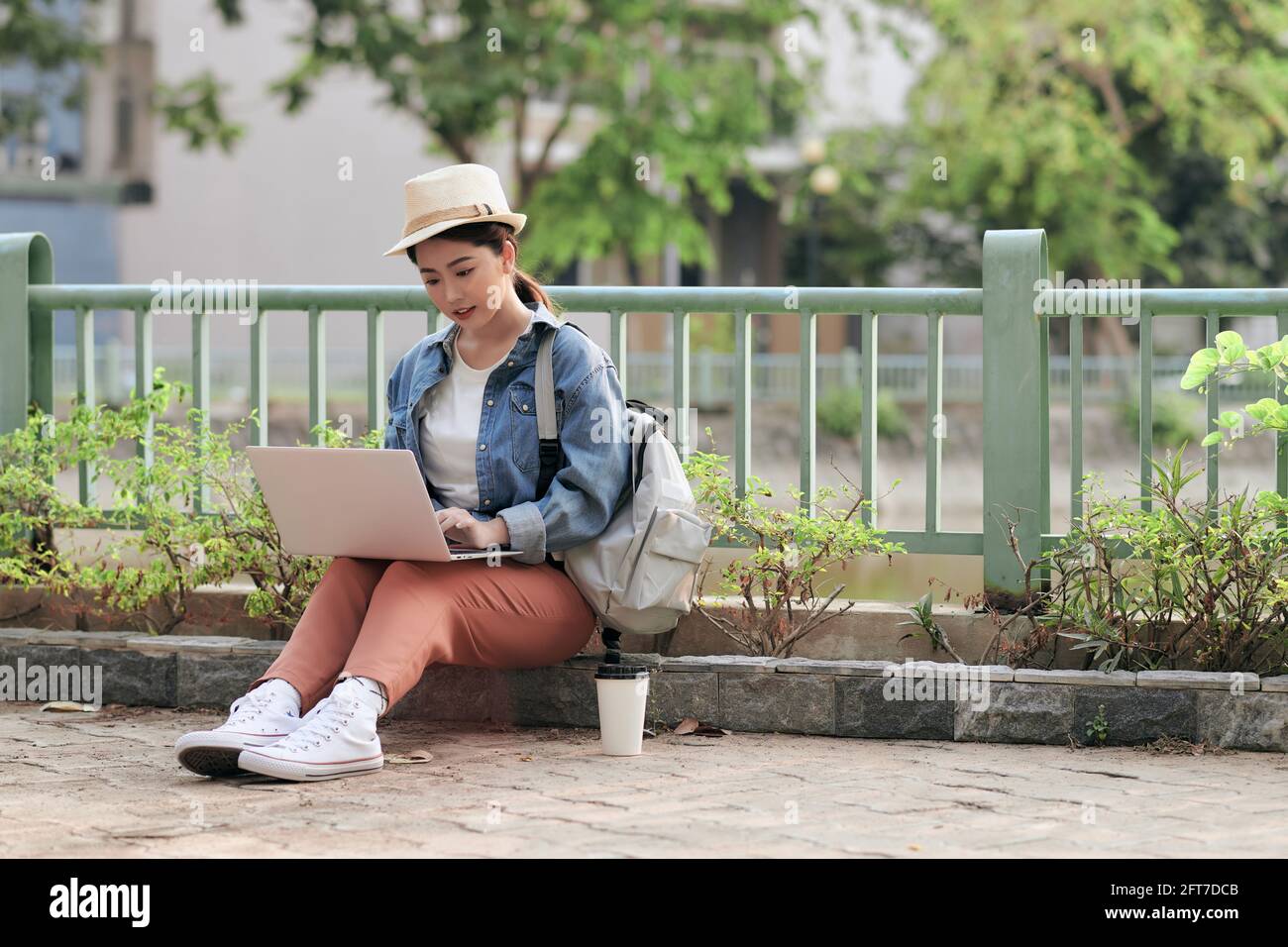 Concentré au travail. Jeune femme asiatique confiante, vêtue d'un ordinateur portable pour apprendre à distance où que vous soyez, tout en étant assise sur le ci Banque D'Images