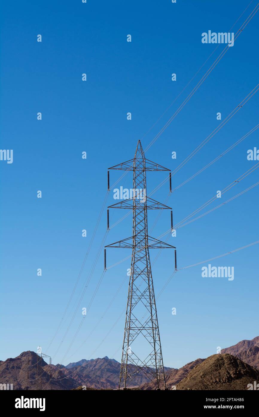 Support électrique des câbles d'alimentation haute tension. Support métallique avec isolateurs haute tension et contre le ciel bleu dans le désert avec collines et mounta Banque D'Images