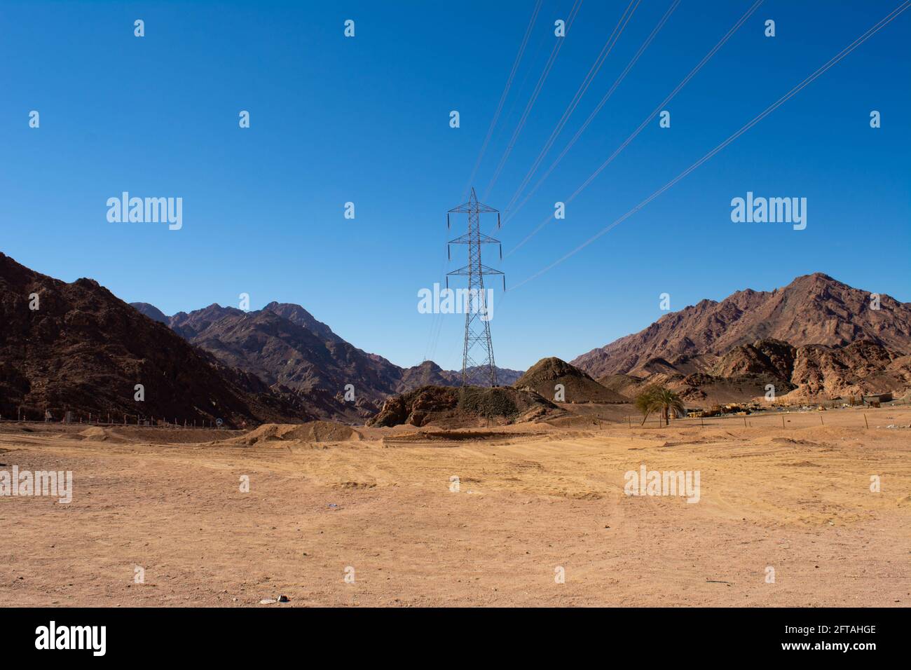 Support électrique des câbles d'alimentation haute tension. Support métallique avec isolateurs haute tension et contre le ciel bleu dans le désert avec collines et mounta Banque D'Images