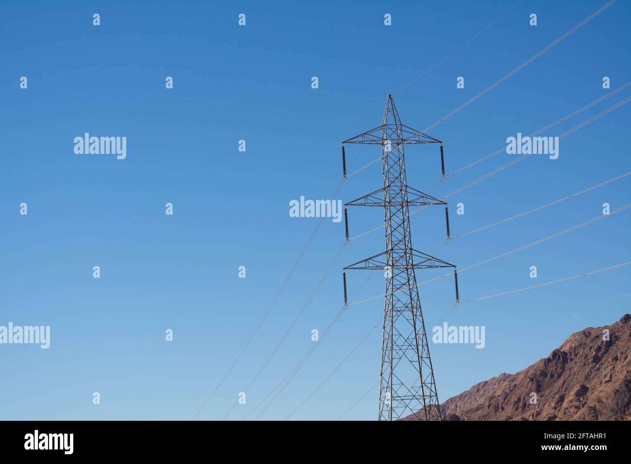Support électrique des câbles d'alimentation haute tension. Support métallique avec isolateurs haute tension et contre le ciel bleu dans le désert avec collines et mounta Banque D'Images