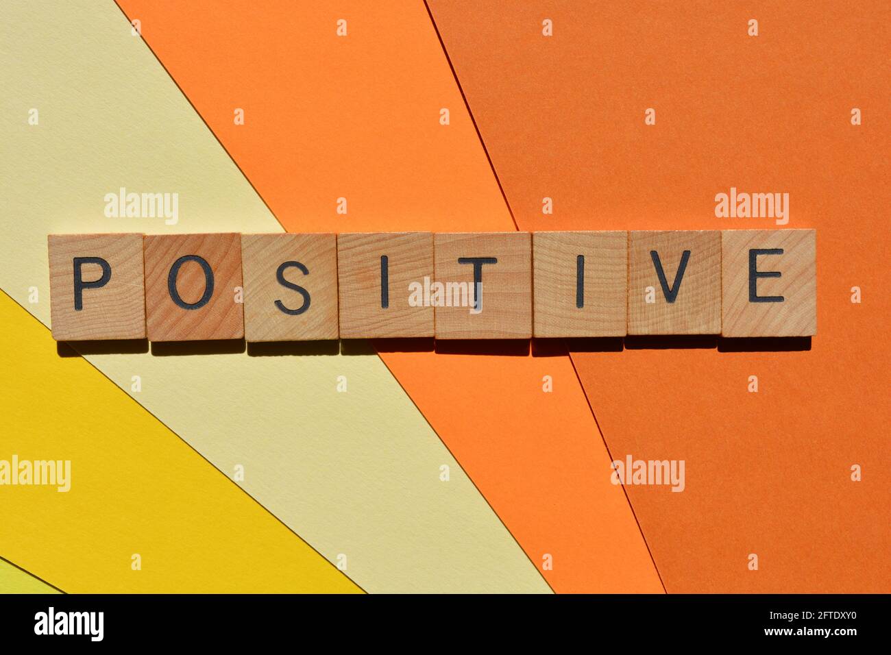 Positif, mot en lettres de l'alphabet de bois isolées sur fond coloré Banque D'Images