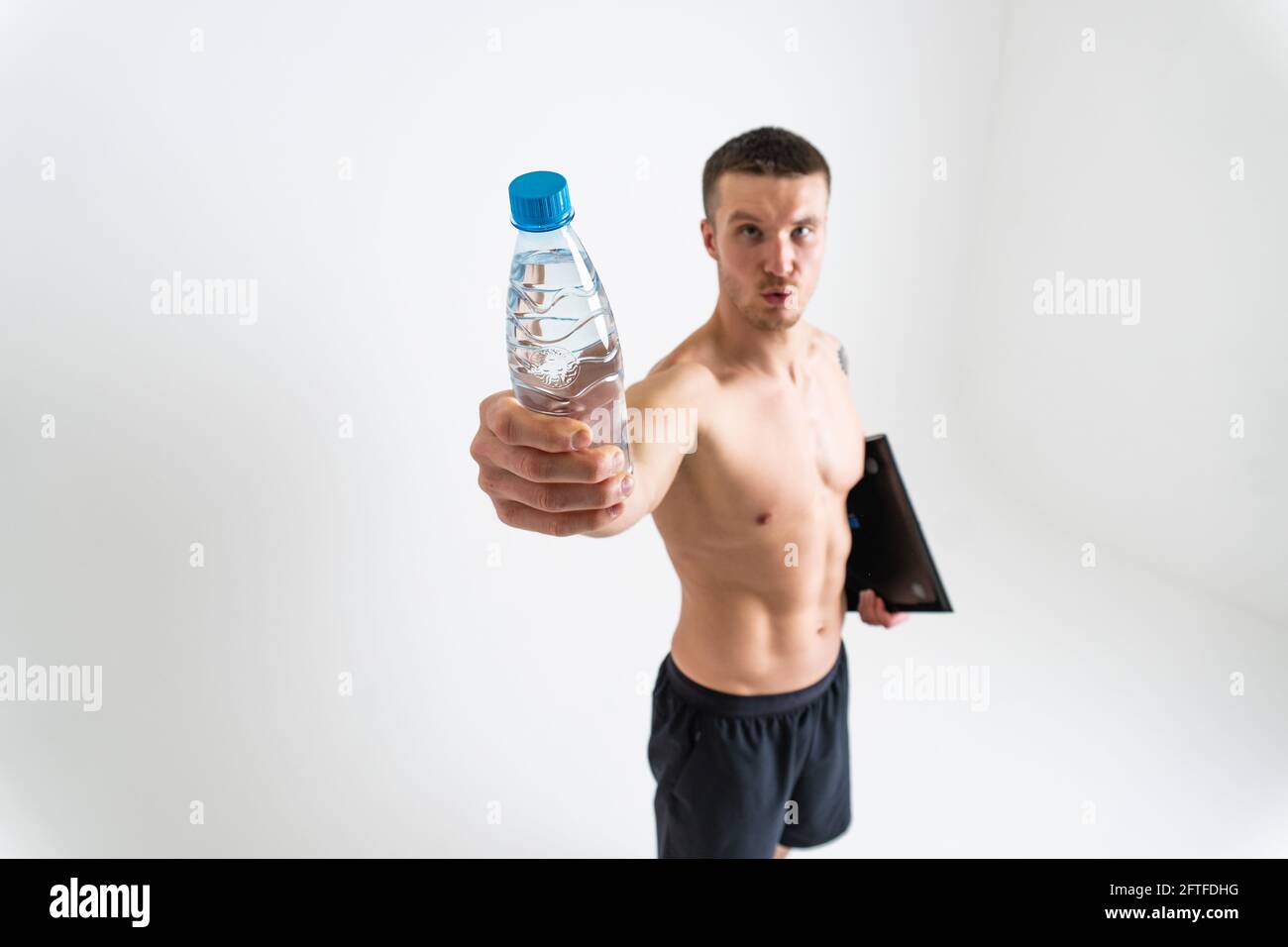 La forme physique de boisson-eau est pompée avec une serviette sur un fond blanc isolé de santé d'entraînement d'ajustement, l'énergie de l'eau de nutrition gars, la force de fond p Banque D'Images